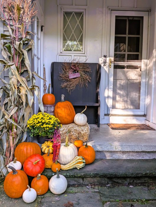 Fall pumpkins, mums and cornstalks arranged at a home entrance