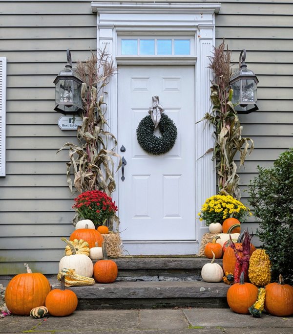Fall pumpkins, mums and cornstalks arranged at a home entrance