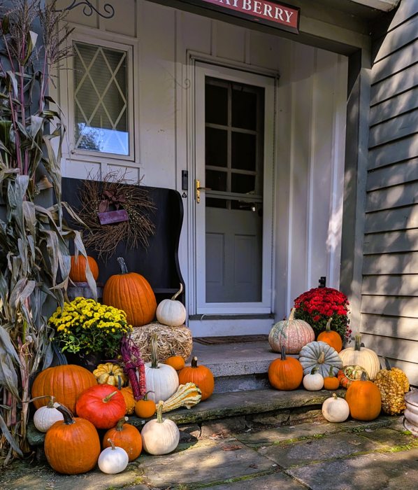 Fall pumpkins, mums and cornstalks arranged at a home entrance