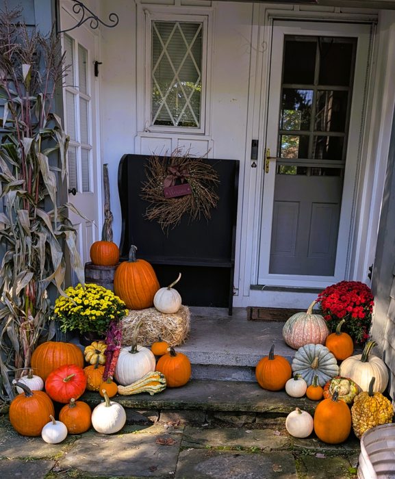 Fall pumpkins, mums and cornstalks arranged at a home entrance