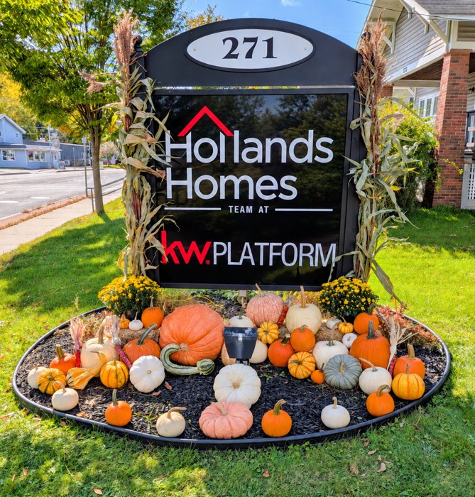 Pumpkins, mums and cornstalks surrounding a local real estate office sign