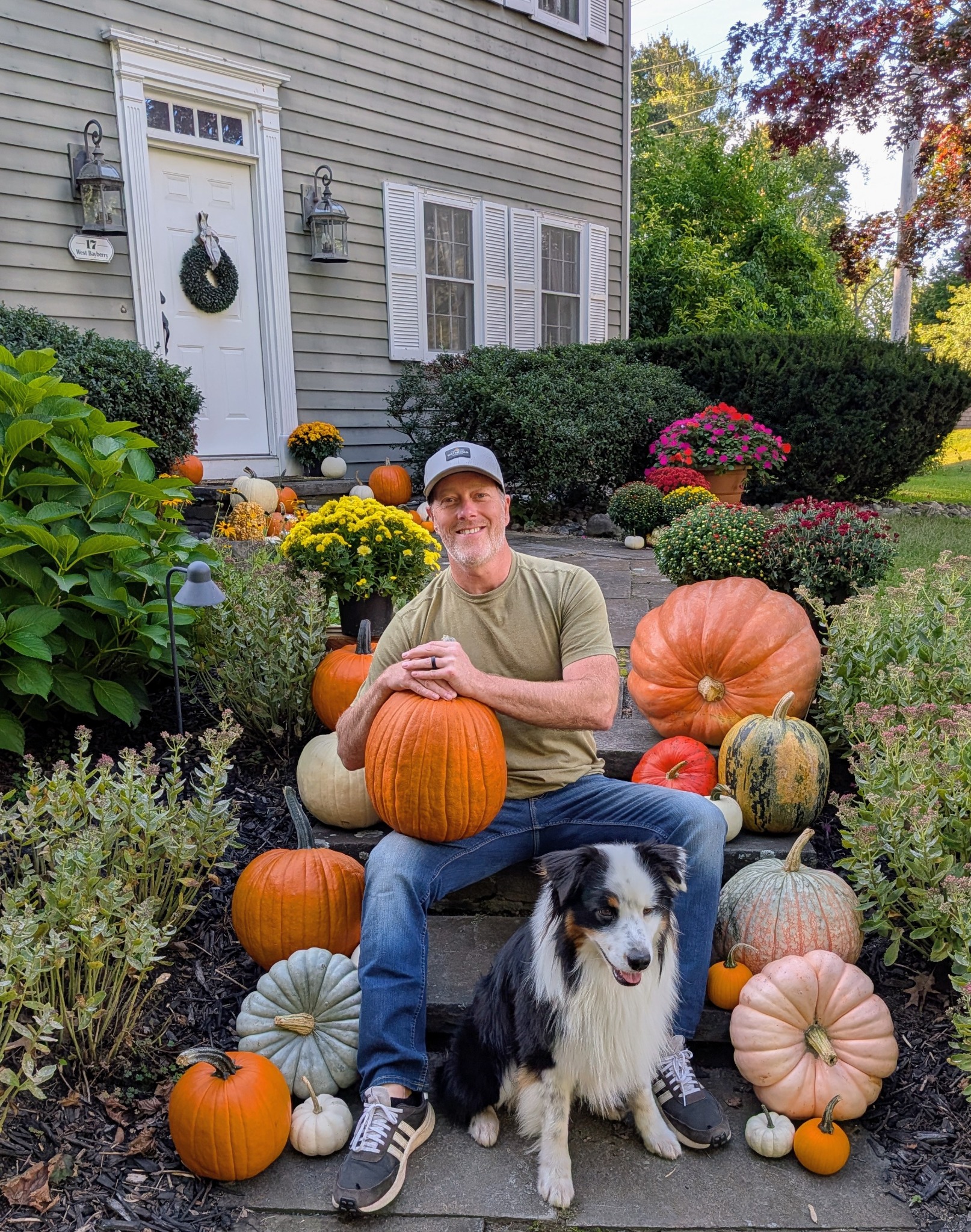 Jared with his dog, surrounded by pumpkins and mums on the front steps.